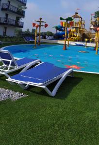 米兹多洛杰Bel Mare Patio and Garden C110的一个带蓝色躺椅的游泳池和一个游乐场