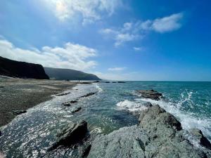 阿伯里斯特威斯Chalet Kiss of the Sea的阴天有岩石和海洋的海滩