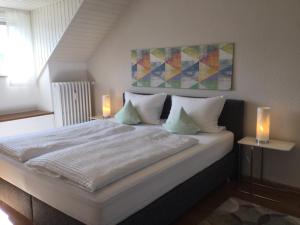 梅灵Gästehaus Weber-Loskill的一间卧室配有一张带两个蜡烛的大型白色床。