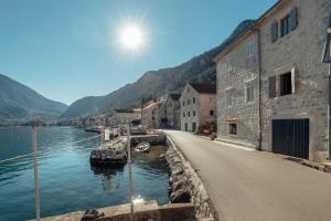 科托尔18th Century Villa in the UNESCO Bay of Kotor的一条有建筑物的街道,旁边是水体