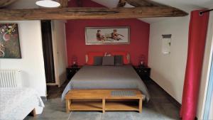 莱瑟佩瑟Au Petit Bignon的一间卧室配有一张红色墙壁的床和一张桌子