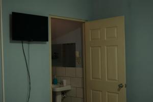 马那瓜Hotel Valerie的门旁的墙上有电视的浴室