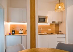 IttenheimCosyBNB bleu, logement indépendant, wifi, parking, petit déjeuner的厨房配有白色橱柜、桌子和微波炉