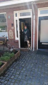 图贝尔亨B&B Bij de koeien的一只猫站在房子门口的女人