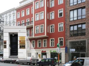 柏林Boutique Hotel Mittendrin Berlin的一座红色的建筑,前面有汽车停放