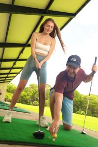 图卢姆Xaha Villas Suites & Golf Resort的打高尔夫的男人和女人