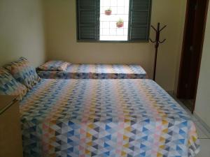 巴乌鲁Casa - Chácara Bella Arraes的一间卧室配有一张带五颜六色棉被的床