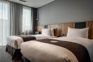 SejongBest Western Plus Hotel Sejong的酒店客房设有两张床和窗户。