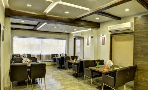 艾哈迈达巴德阿兰果园酒店的餐厅设有桌椅和大窗户。