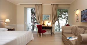的里雅斯特马克西米利安里维埃拉酒店 的酒店客房配有一张床、一张沙发和一张书桌。