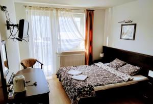 韦巴Willa Latarnik的一间卧室配有一张床、一张桌子和一个窗户。
