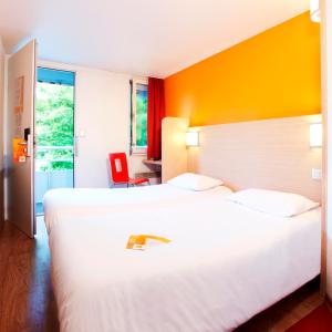 圣马丹-布洛涅Première Classe Boulogne sur Mer的酒店客房,设有两张床和一张红色椅子