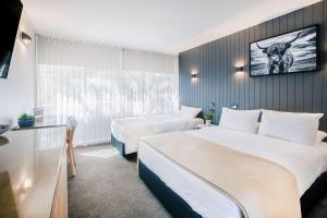 阿米代尔City Centre Motel Armidale的酒店客房设有两张床和一台墙上的电视。