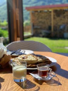 LibrazhetAlbanian traditional Villa的一张桌子,上面放着一盘食物和两杯牛奶
