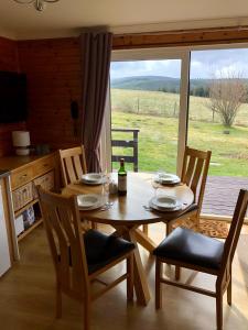AuchnastankBen Rinnes Lodge Glenlivet Highlands的一张带椅子的木桌和一瓶葡萄酒