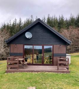 AuchnastankBen Rinnes Lodge Glenlivet Highlands的小屋设有大窗户和木甲板