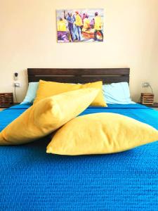 明德卢Casa Bom Dia的一张带黄色枕头和蓝色毯子的床