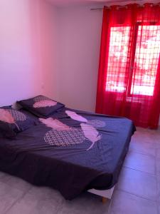 耶尔Propriété Rebardo的一间卧室配有一张带蓝色毯子和红色窗帘的床