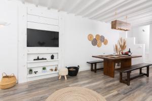 Megali AmmosWhitelist Loft in Mykonos Town的一间设有桌子的用餐室和墙上的电视