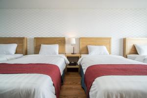 西归浦市微风湾酒店的客房设有两张床和一张带台灯的桌子。