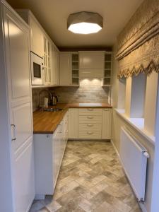 帕兰加Vaineikio 8的厨房配有白色橱柜和瓷砖地板。