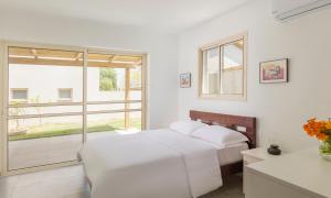 Tal ShaẖarTal Shahar Zimmers的一间白色卧室,配有两张床和窗户