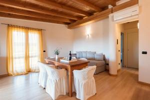 圣温琴佐博德勒拉嘎维农庄的客厅配有木桌和白色椅子