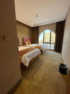 利雅德Hosta Hotel Suites的酒店客房设有两张床和大窗户。
