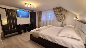 杜劳Pensiunea Mădălina的卧室配有一张白色大床和一台平面电视。