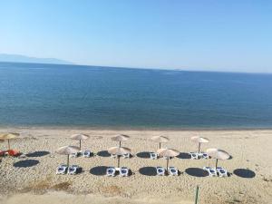 内亚卡瓦里Ammos Apartments的海滩上的一组椅子和遮阳伞