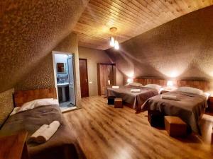 卡兹贝吉Kazbegi Inn的一间铺有木地板的客房内配有三张床的卧室