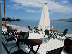 艾拉方索斯Hotel Elafonisos的一组桌椅,上面有一把伞和大海
