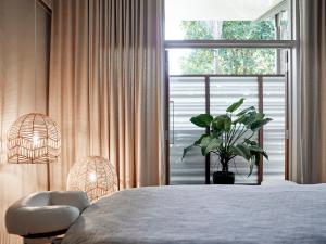 拜伦湾Crystalbrook Byron的一间卧室,配有一张带植物和窗户的床