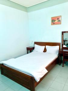 芽庄Thien Phuc Hotel的一间卧室配有一张带白色床单和镜子的床