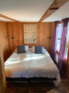 BorensbergTorpa Gård的卧室配有一张床铺,位于带木墙的房间内