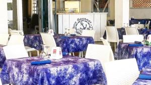 锡代诺滨海Petit gourmet的一组桌子和白色椅子,配有紫色的桌布