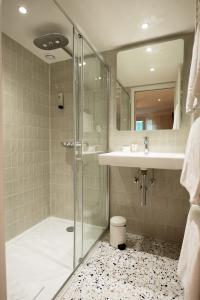 巴黎巴蒂诺勒酒店的一间带玻璃淋浴和水槽的浴室