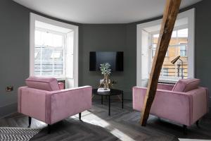 爱丁堡29 Queen Street Luxury Flats的客厅配有粉红色的椅子和电视