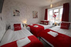 UnstoneHolland House的一间设有两张红色和白色床单的房间