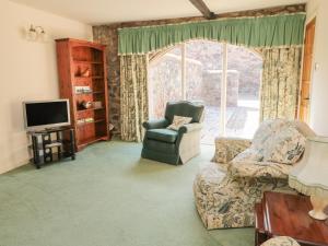 伍勒Lupin Cottage的客厅配有沙发、椅子和电视