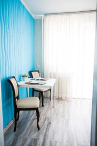 秋明Apartment on Maksima Gorkogo 10的蓝色墙壁的房间里一张桌子和椅子