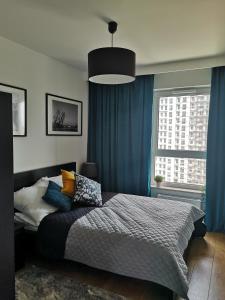 格但斯克Apartamenty 48 Letnica的一间卧室配有一张带蓝色窗帘的大床