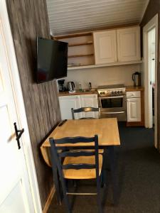 SkasendenFinnskogen hyttegrend的厨房配有木桌,墙上配有电视。