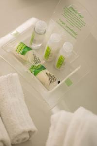 罗萨里奥罗萨里奥假日酒店的浴室水槽配有2瓶漂白剂和毛巾