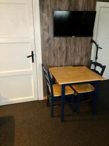 SkasendenFinnskogen hyttegrend的一张木桌,配有两把椅子和墙上的一台电视