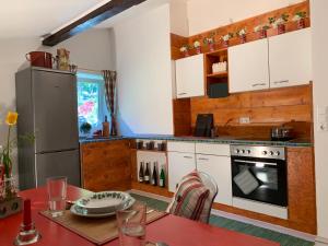 沃尔特湖畔韦尔登Schwalbennest Velden的厨房配有白色橱柜、桌子和冰箱。