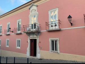 埃尔瓦斯Travassos 11的一座粉红色的建筑,旁边设有阳台