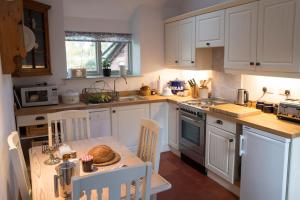 奥斯威斯Courtyard Cottage的厨房配有白色橱柜和一张带面包的桌子。