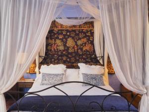 米兰韦尔莫拉达寺乡村民宿的卧室配有带白色窗帘的天蓬床