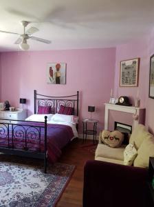 Ségur-le-ChâteauLes Charrons的卧室设有粉红色的墙壁、一张床和一张沙发